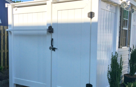 White Vinyl PVC Outdoor Shower attached to side of home. Blacking locking hardware and towel rack on the exterior