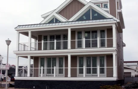 Side of a home with brown siding, VueTube on the first and second floor porch and glass railing. Cellular PVC posts on all railing.