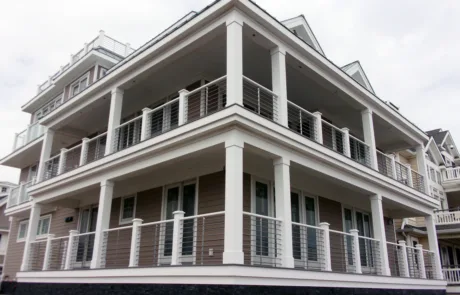 Side of a home with brown siding, VueTube on the first and second floor porch and glass railing on the bedroom balcony and other balconies. Cellular PVC posts on all railing.