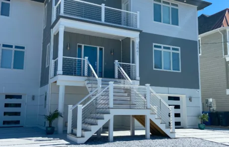 Front of a Home with a landing leading up to the front door and two sets of stairs on each side. Silver anodized VueTube along the stairs, landing and second floor balcony.