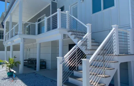 Backyard of home with a set of stairs leading up to the back porch. Porch is raised with Columns. Silver anodized VueTube is along the stairs, porch, second story large balcony