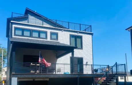 Front of a home with Black VueTube Railing up the stairs and along the first floor balcony and second floor balcony. Large balconys with American Flag hanging from the bottom one.