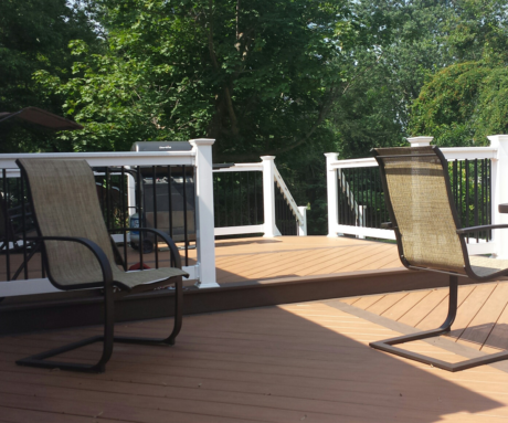 Black Round Balusters with PVC Railings on brown deck with tan outdoor chairs.